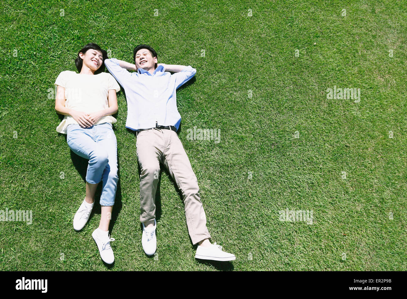 Happy Japanese couple laying on grass in a park Stock Photo - Alamy