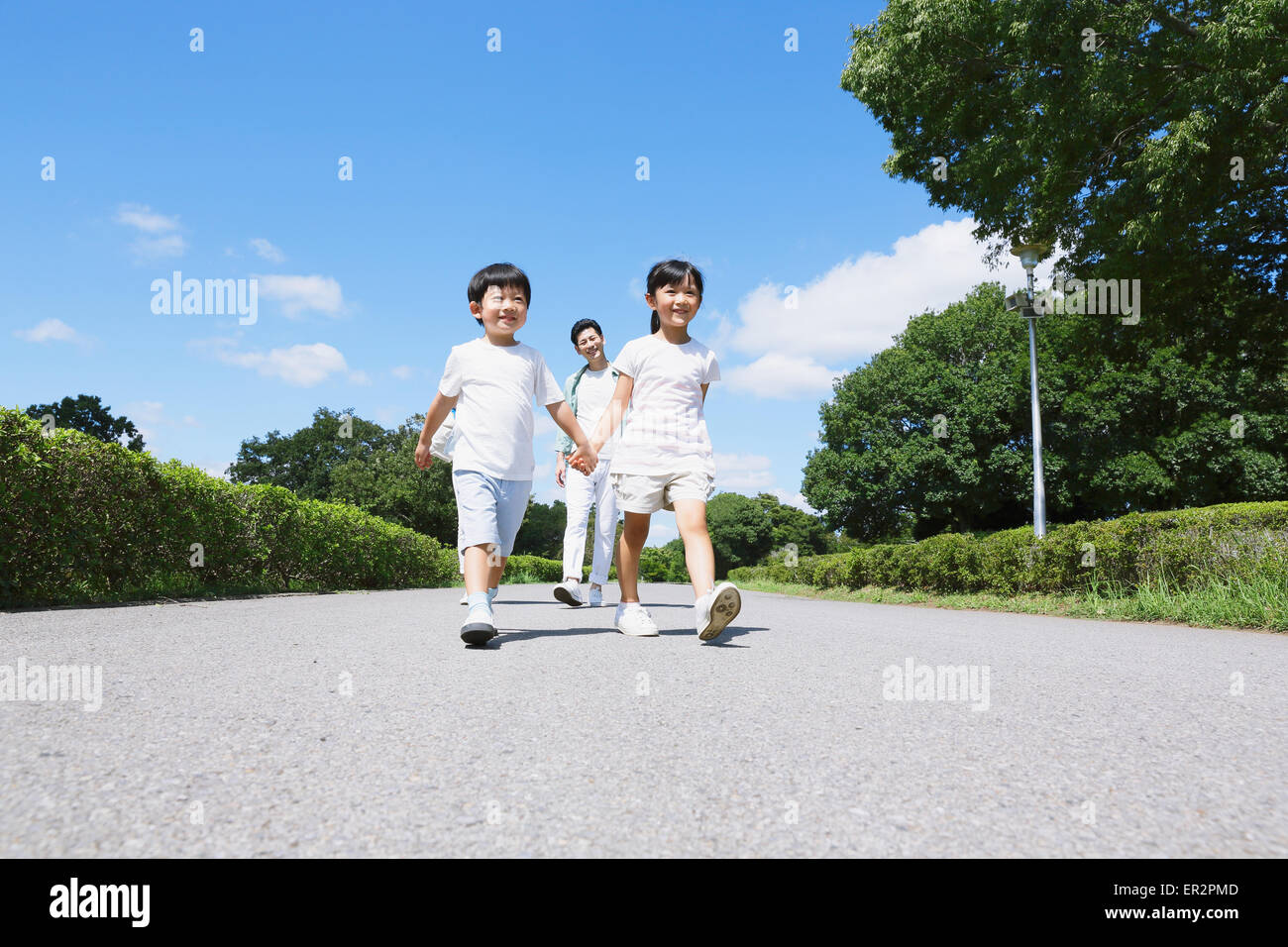 Japanese father playing with his kids in a city park Stock Photo