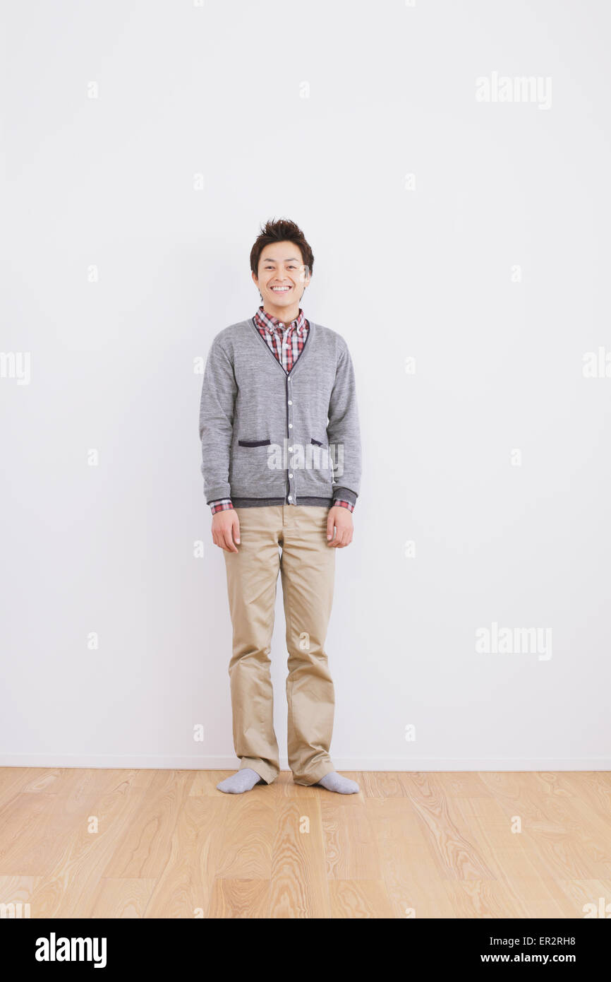 Young adult man standing in front of a white wall Stock Photo - Alamy