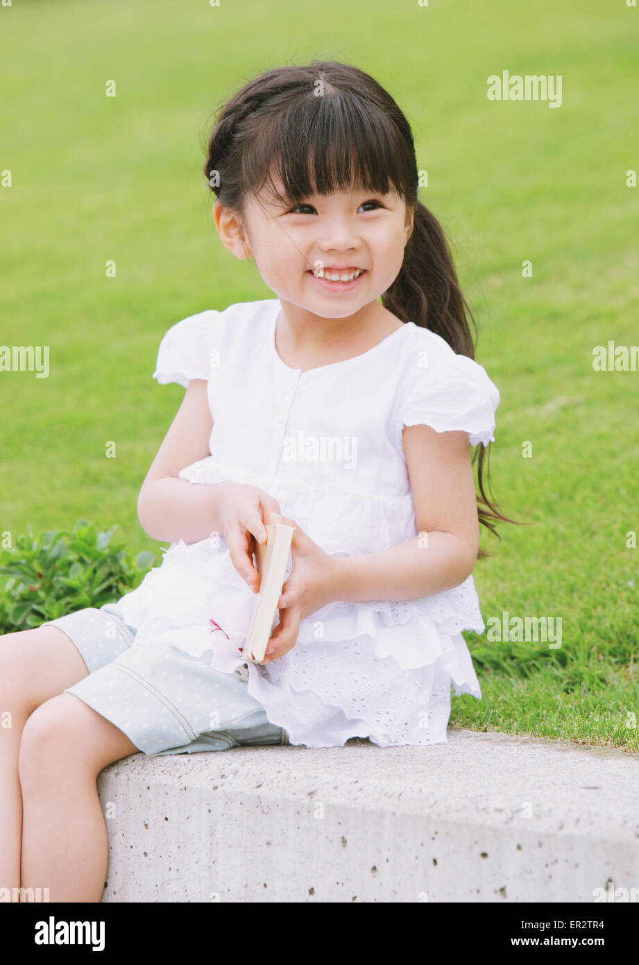Young girl sitting with a book Stock Photo - Alamy