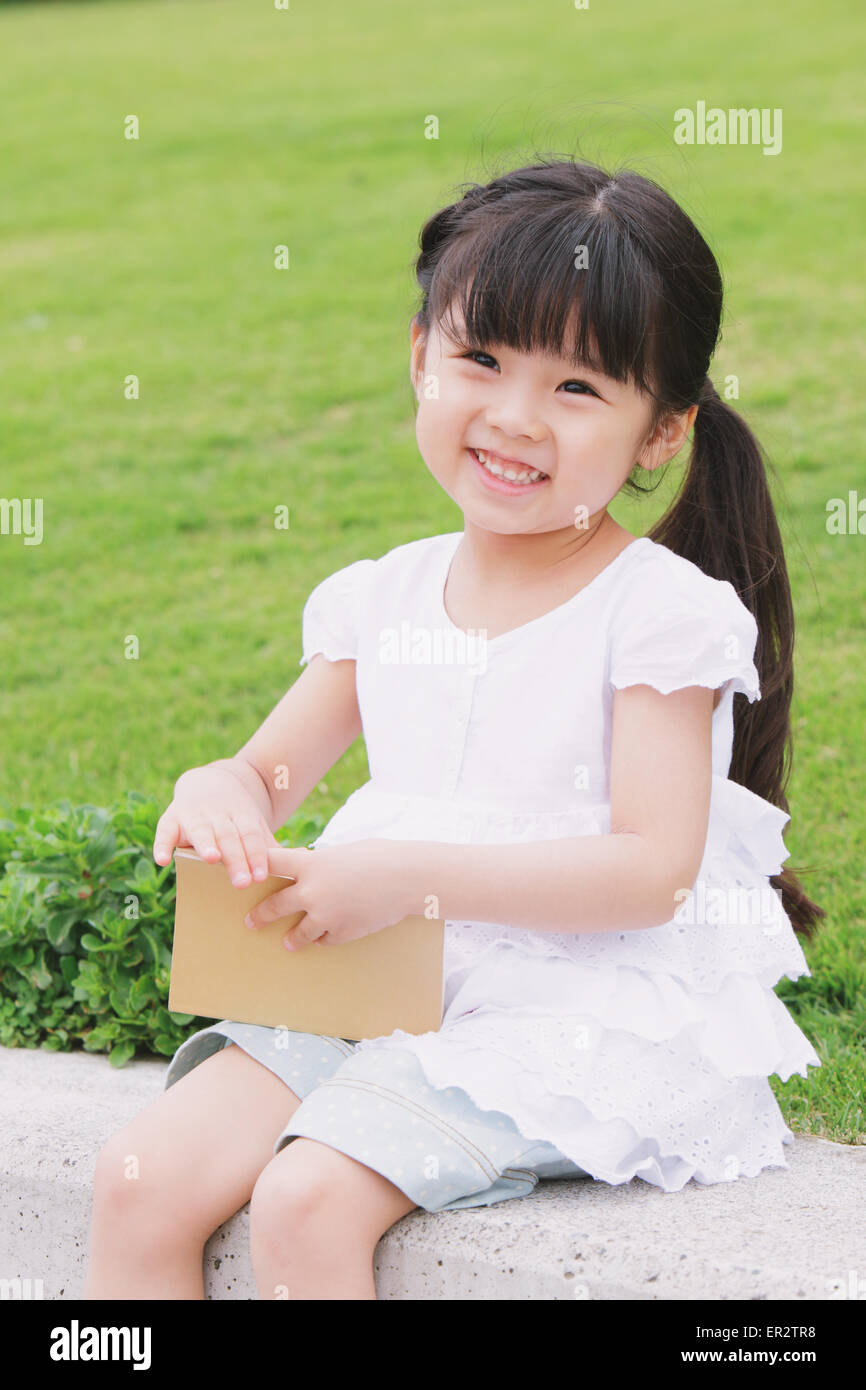 Young girl sitting with a book Stock Photo - Alamy