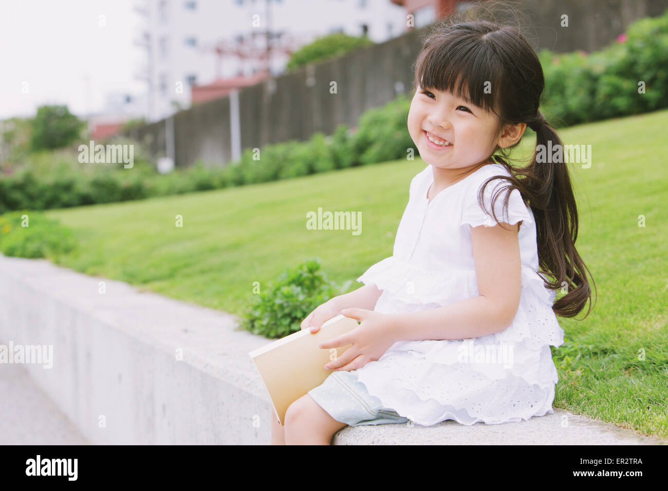 Young girl sitting with a book Stock Photo - Alamy