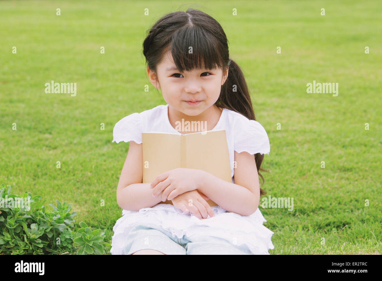 Young girl sitting with a book Stock Photo - Alamy