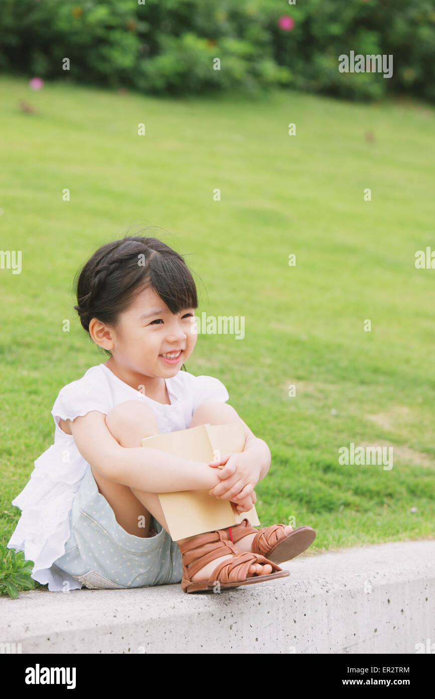 Young girl sitting with a book Stock Photo - Alamy