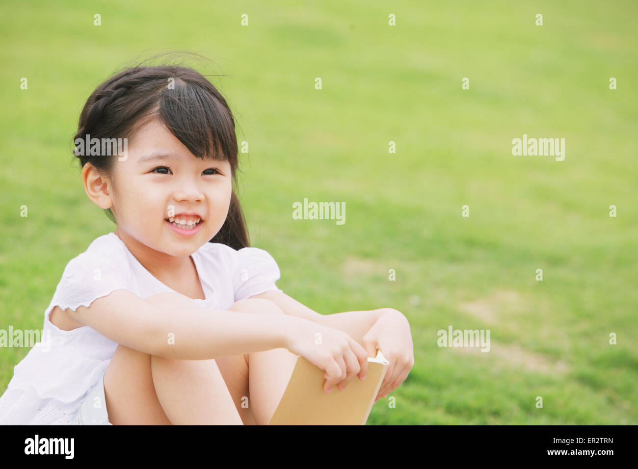 Young girl sitting with a book Stock Photo - Alamy