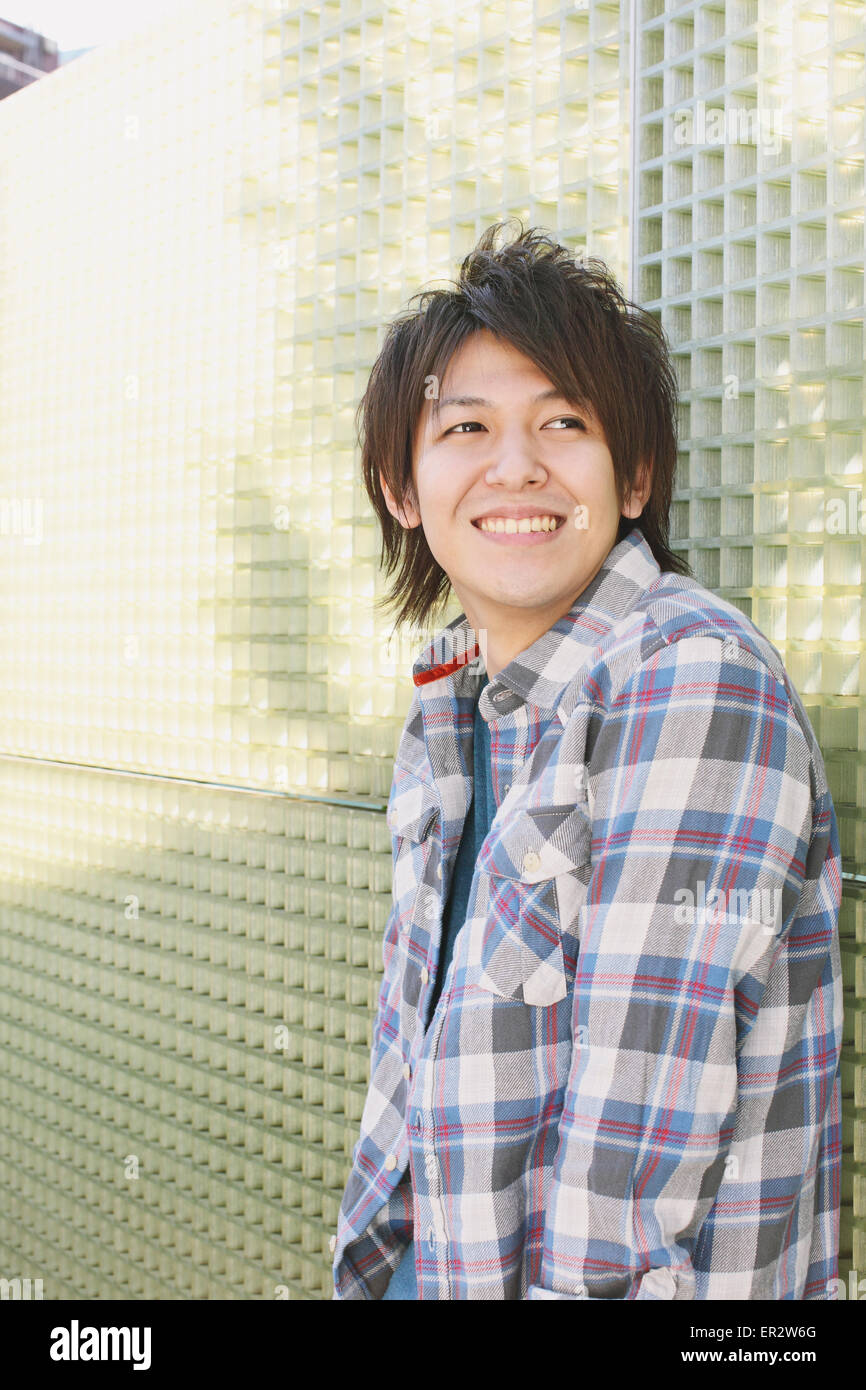 Young man leaning against a wall Stock Photo - Alamy