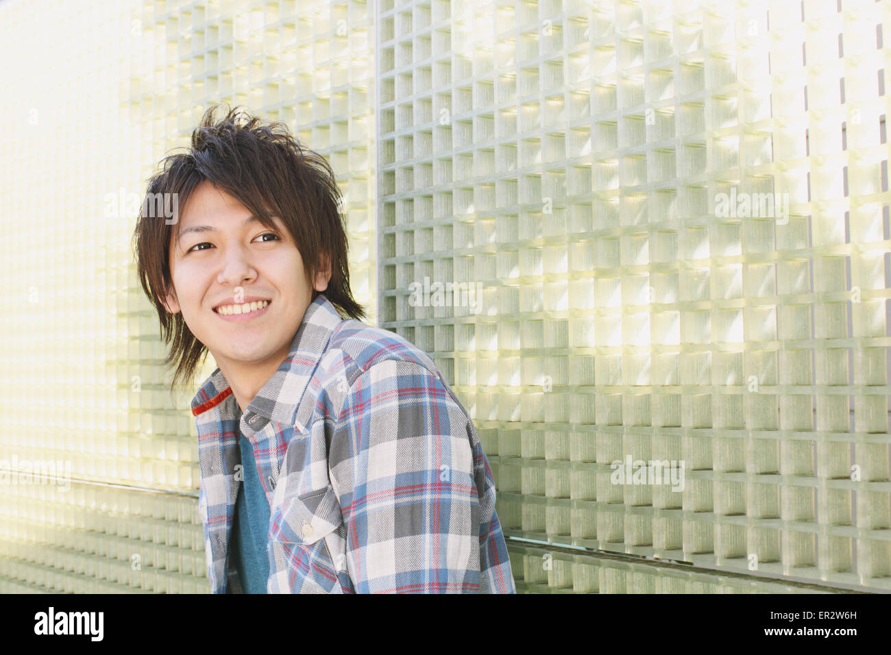 Young man leaning against a wall Stock Photo - Alamy