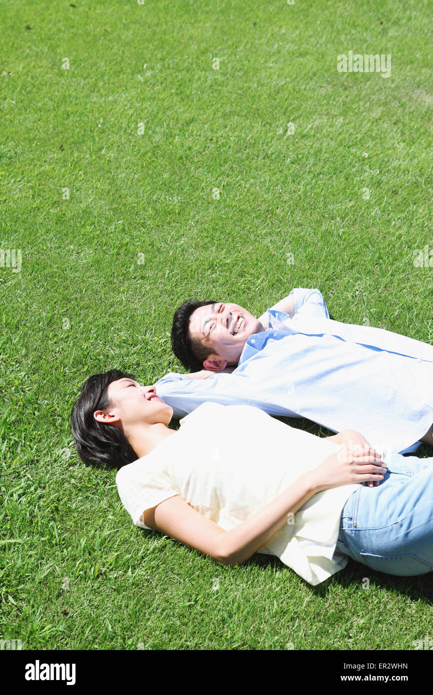 Happy Japanese couple laying on grass in a park Stock Photo - Alamy