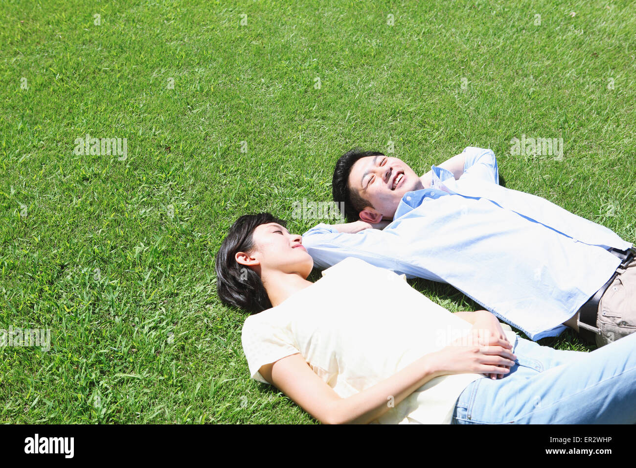 Happy Japanese couple laying on grass in a park Stock Photo - Alamy