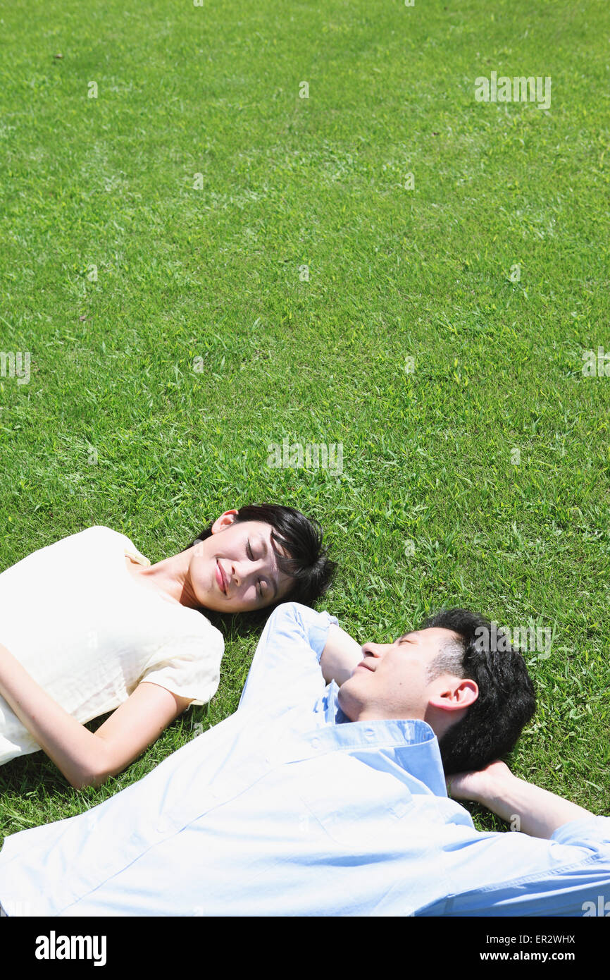 Happy Japanese couple laying on grass in a park Stock Photo - Alamy