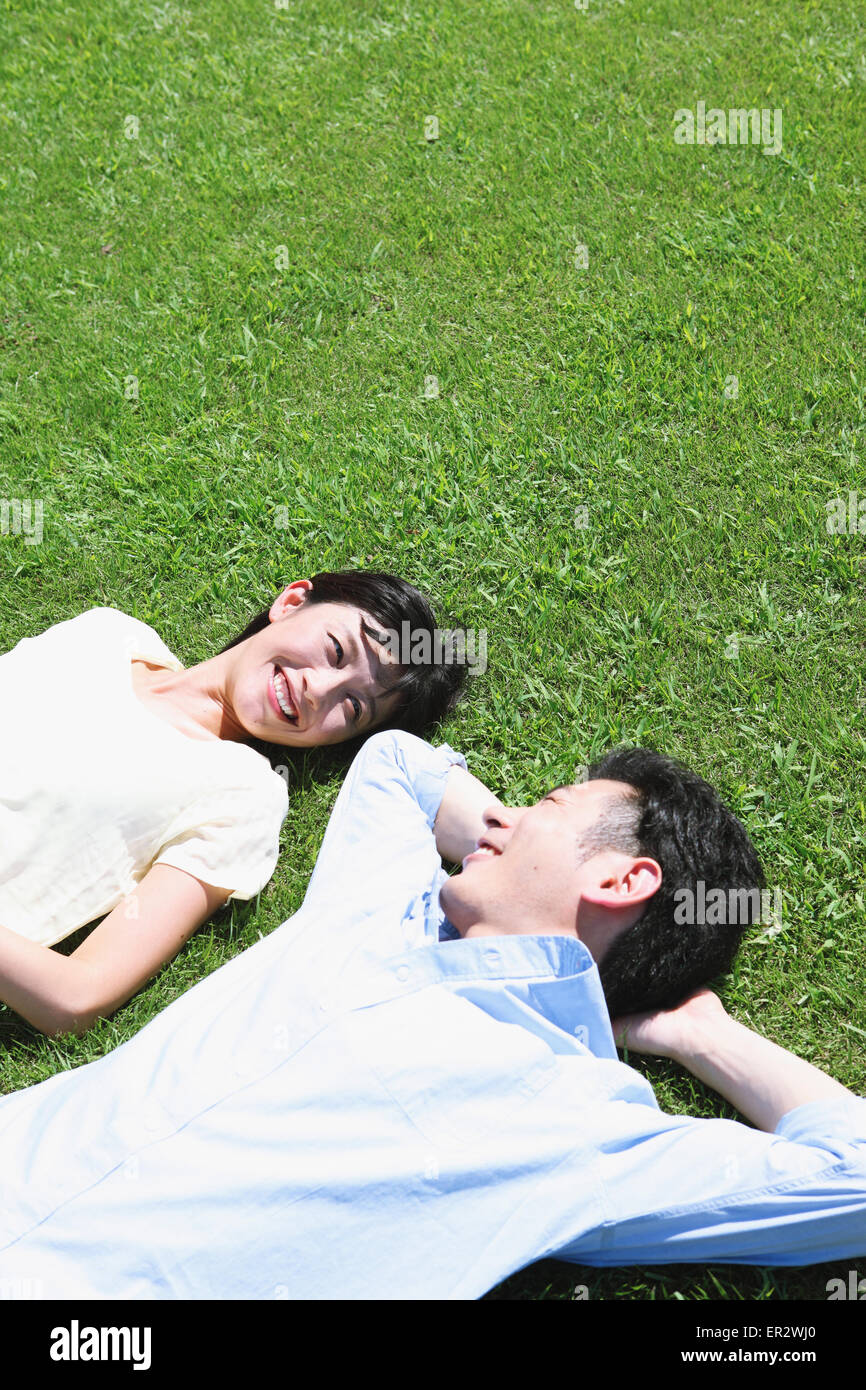 Happy Japanese couple laying on grass in a park Stock Photo - Alamy