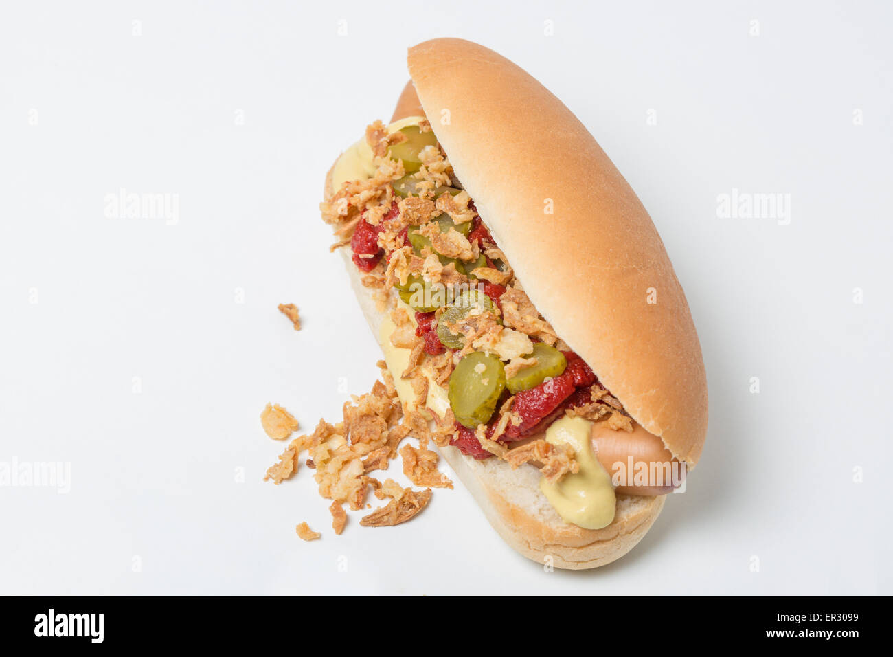 Hot Dog sausage in a bun with roasted onions, pickles, ketchup and mustard on white background Stock Photo