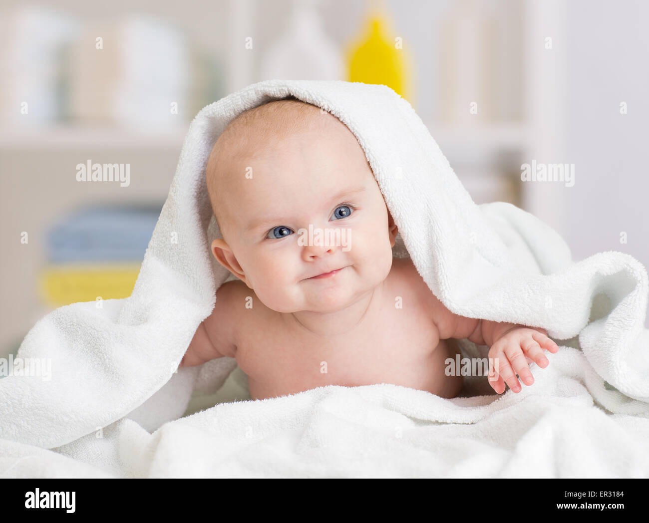 smiling baby girl lying under towel Stock Photo Alamy