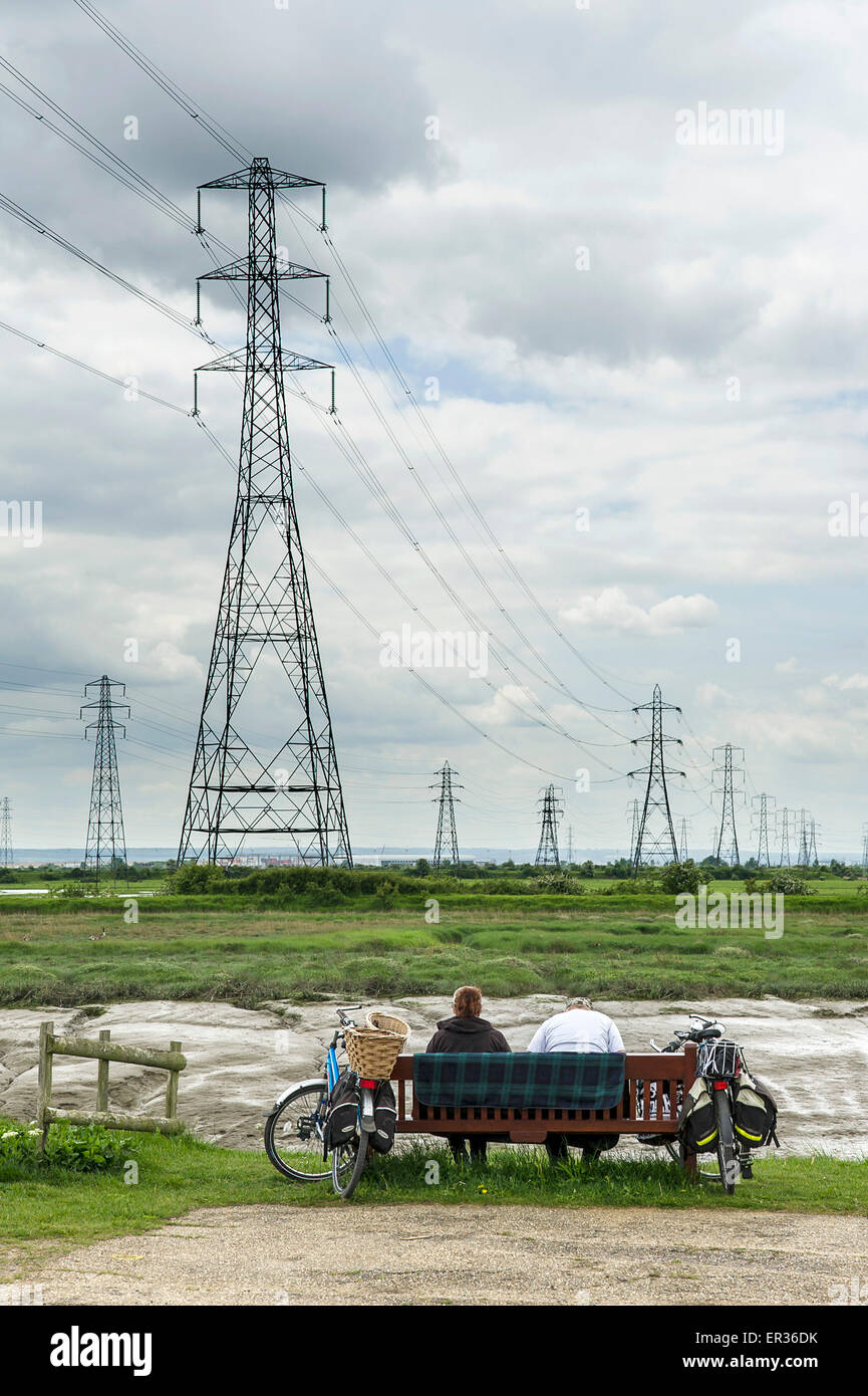 Two people sitting on a bench looking out over Vange Creek in Essex. Stock Photo