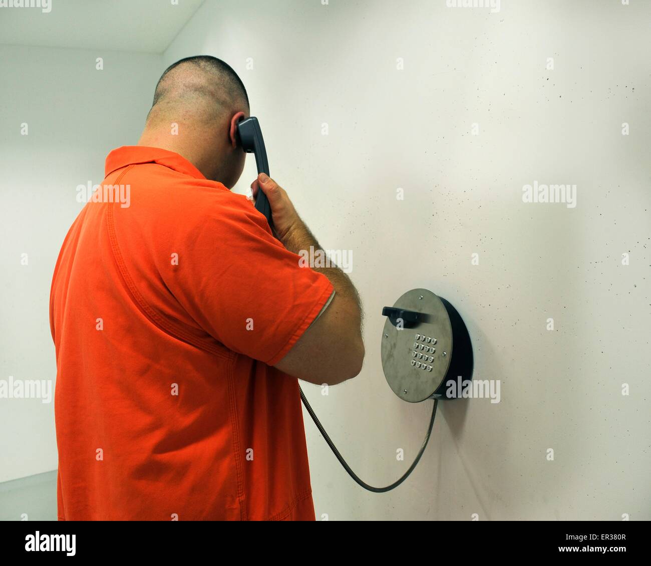 A prisoner in orange jump suit makes a phone call from inside the U.S. Army Regional