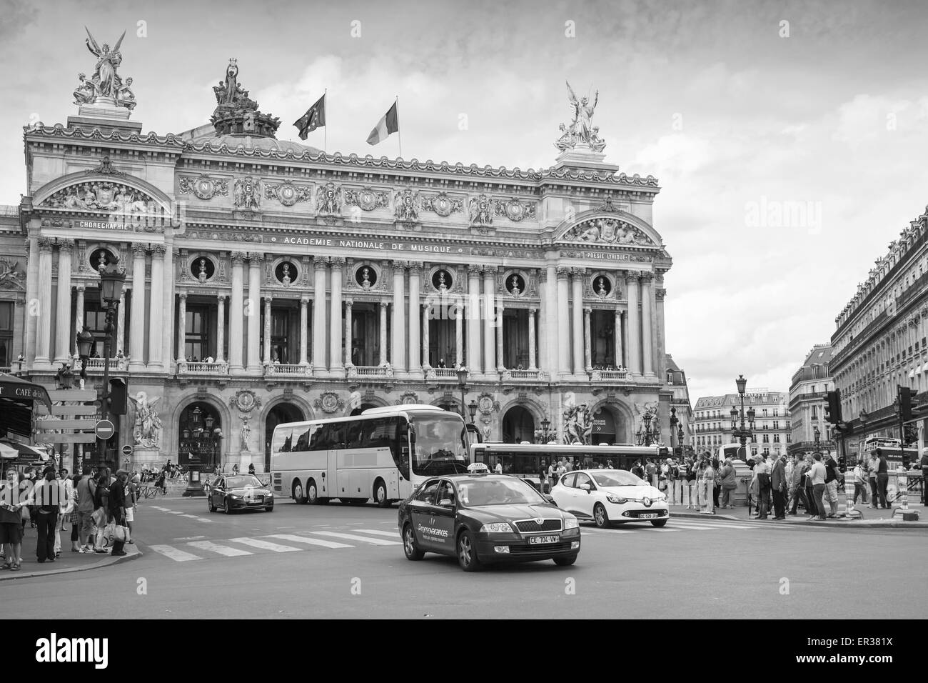 Paris, France - August 09, 2014: Palais Garnier, old Opera house in Paris with walkink people and cars on the street, monochrome Stock Photo