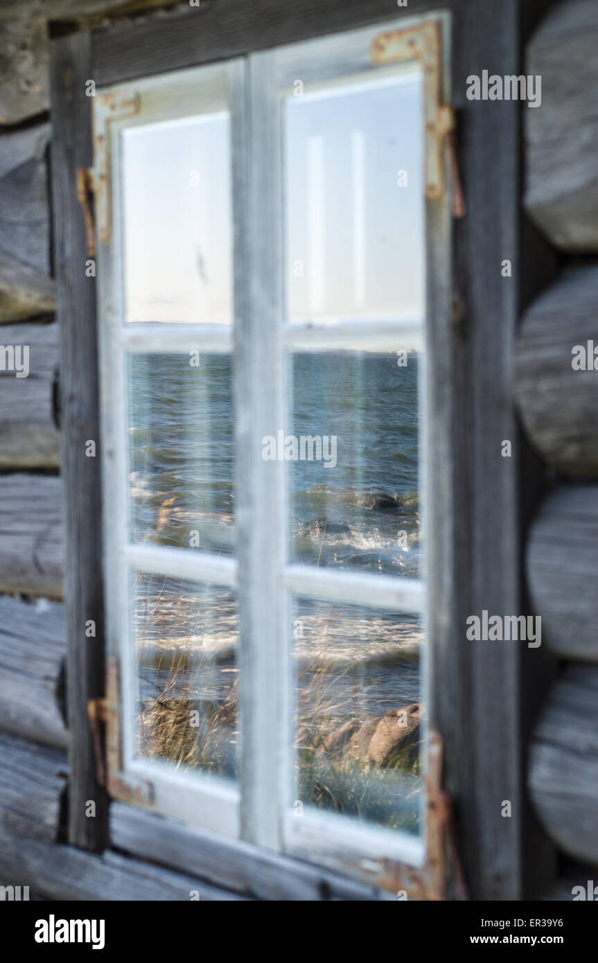 Seashore reflection in rustic cottage window of old wooden piscatorial ...
