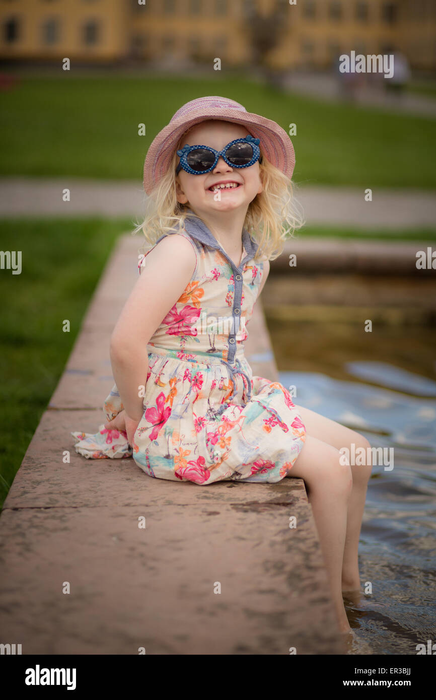 Girl sitting with her feet in water making a face Stock Photo - Alamy