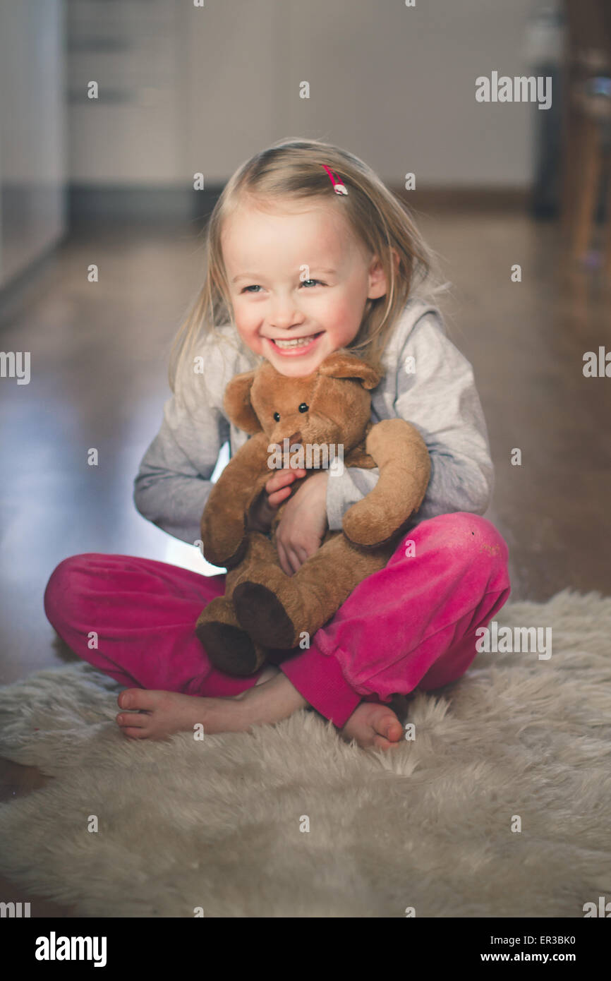 Girl sitting on the floor hugging her teddy bear Stock Photo - Alamy