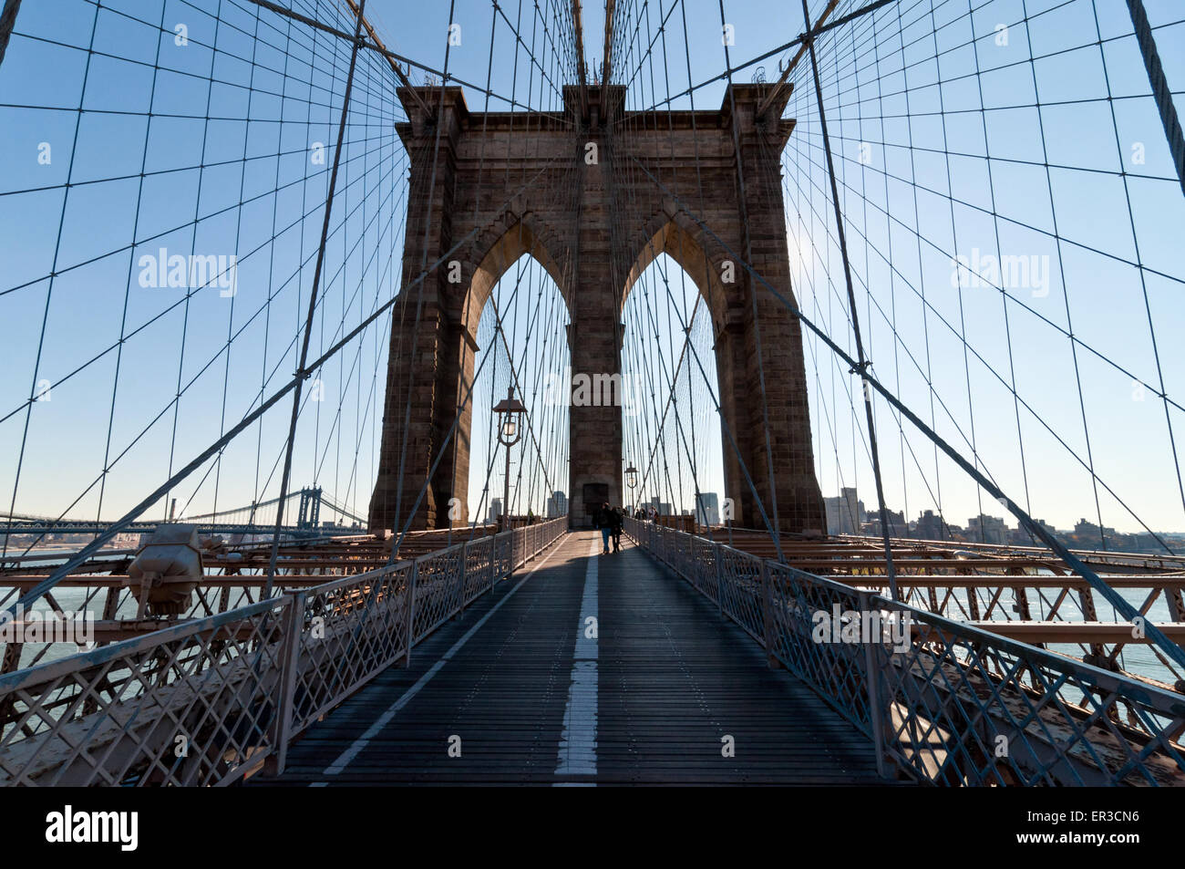 Silhouette of unknown people walking across the Brooklyn Bridge as the ...