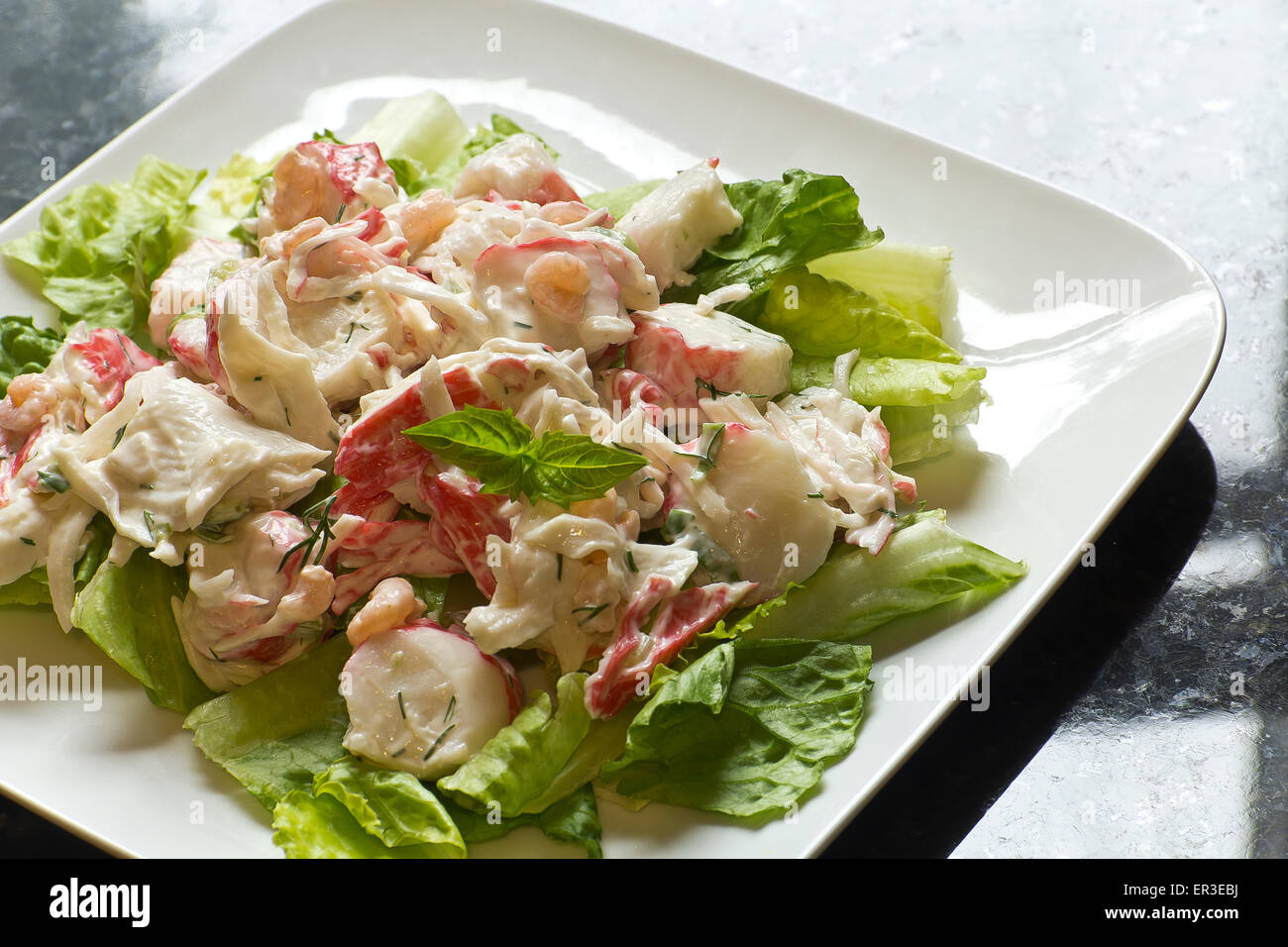 Mayonnaise seafood salad with shrimp and crab meat and fresh dill, romaine lettuce, and basil leaf garnish Stock Photo