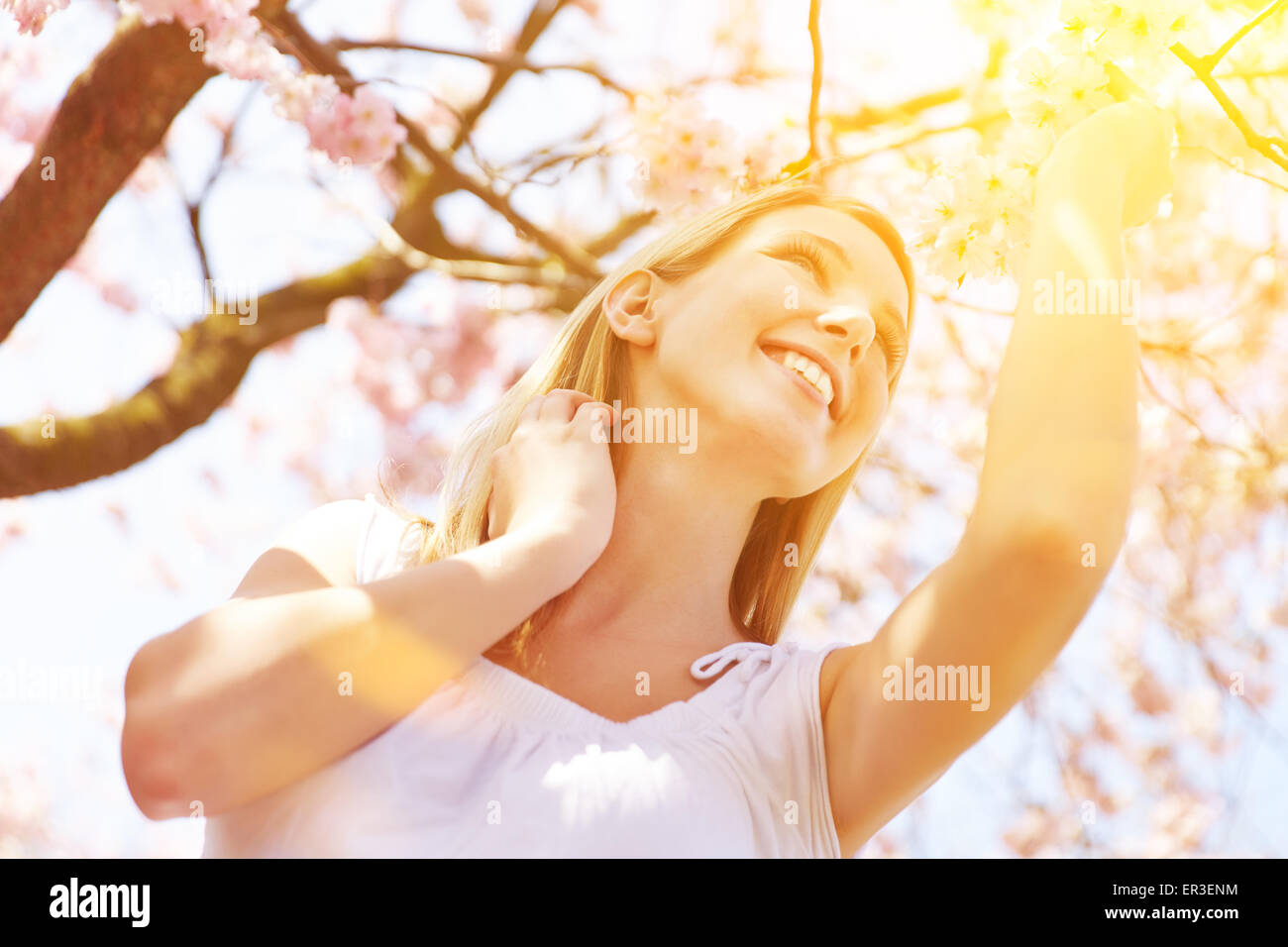 Sunny day with happy young woman under blooming cherry tree in spring ...