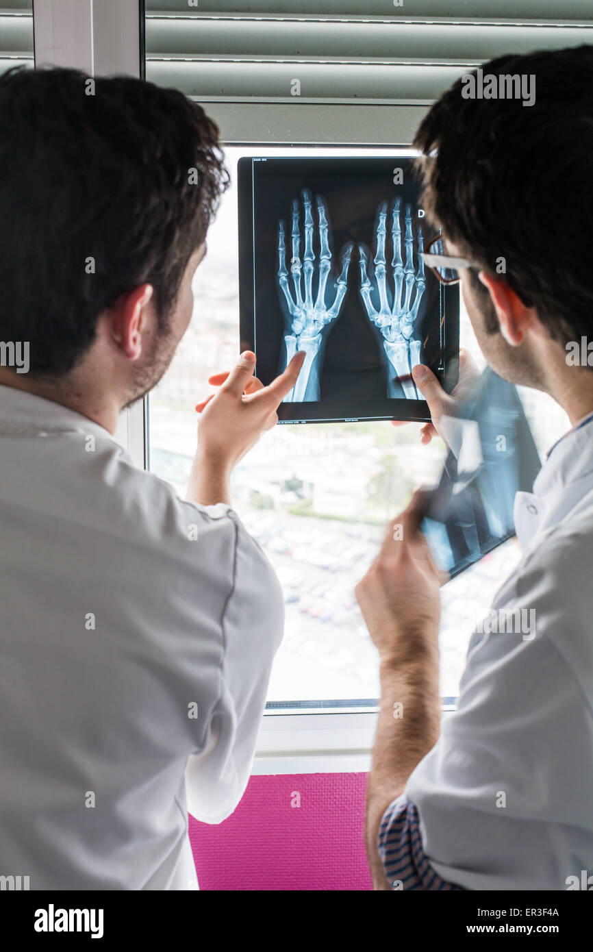 Rheumatologist (right) and internal examining radiographs of the hands of a patient with rheumatoid arthritis, Bordeaux hospital, France. Stock Photo