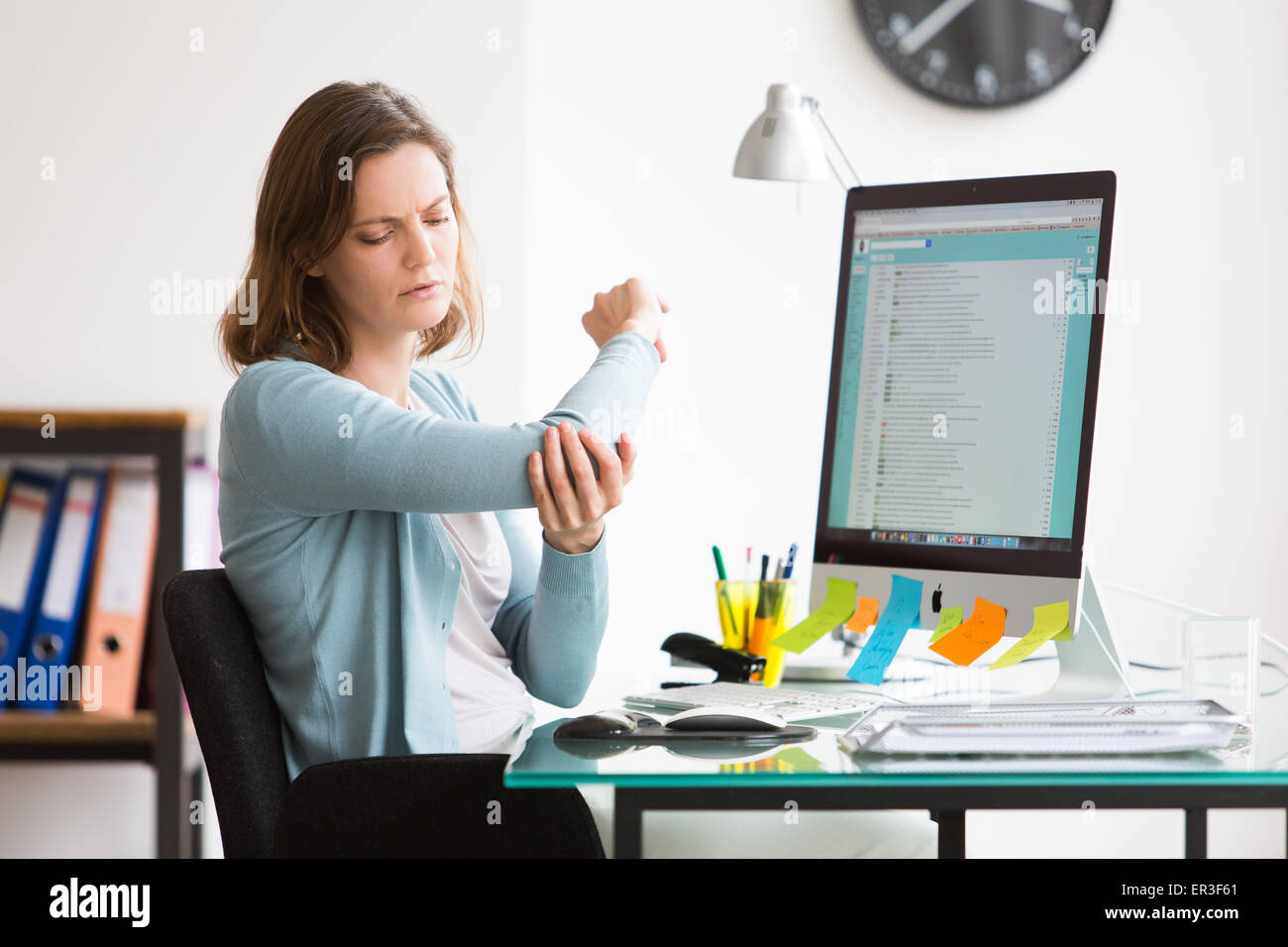 Woman at work suffering from elbow pain. Stock Photo