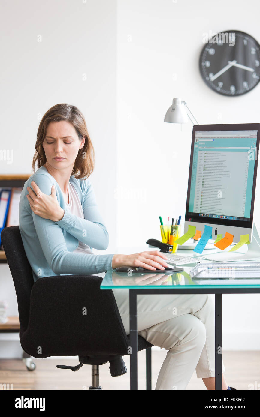 Woman at work suffering from shoulder pain. Stock Photo