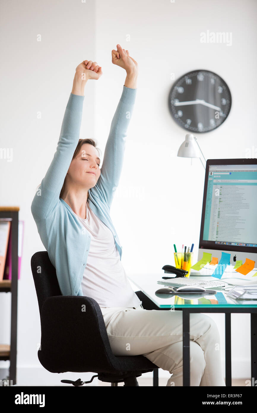 Office woman stretching arms at work. Stock Photo