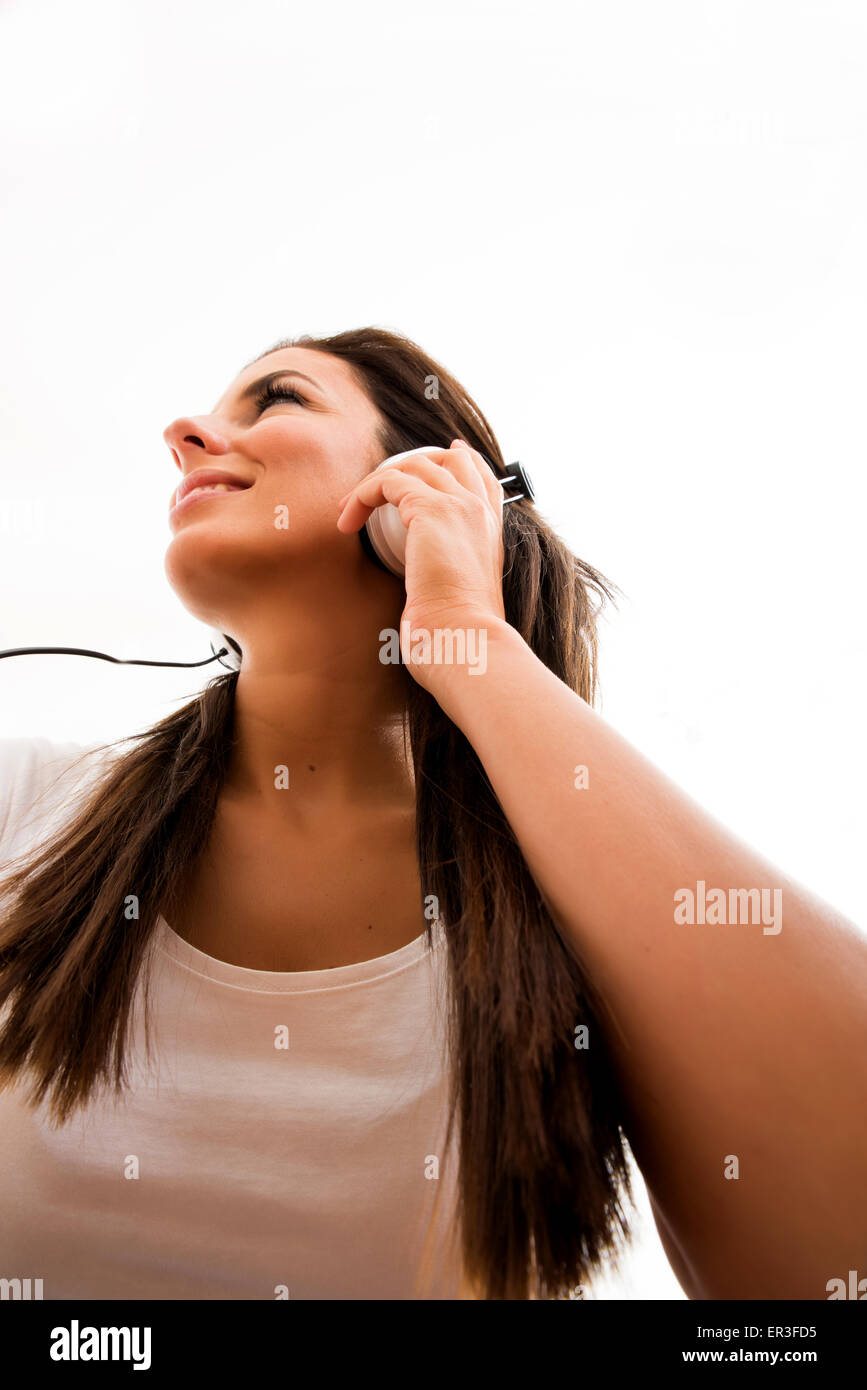 Portrait of a young beautiful woman listening to music with headphones ...