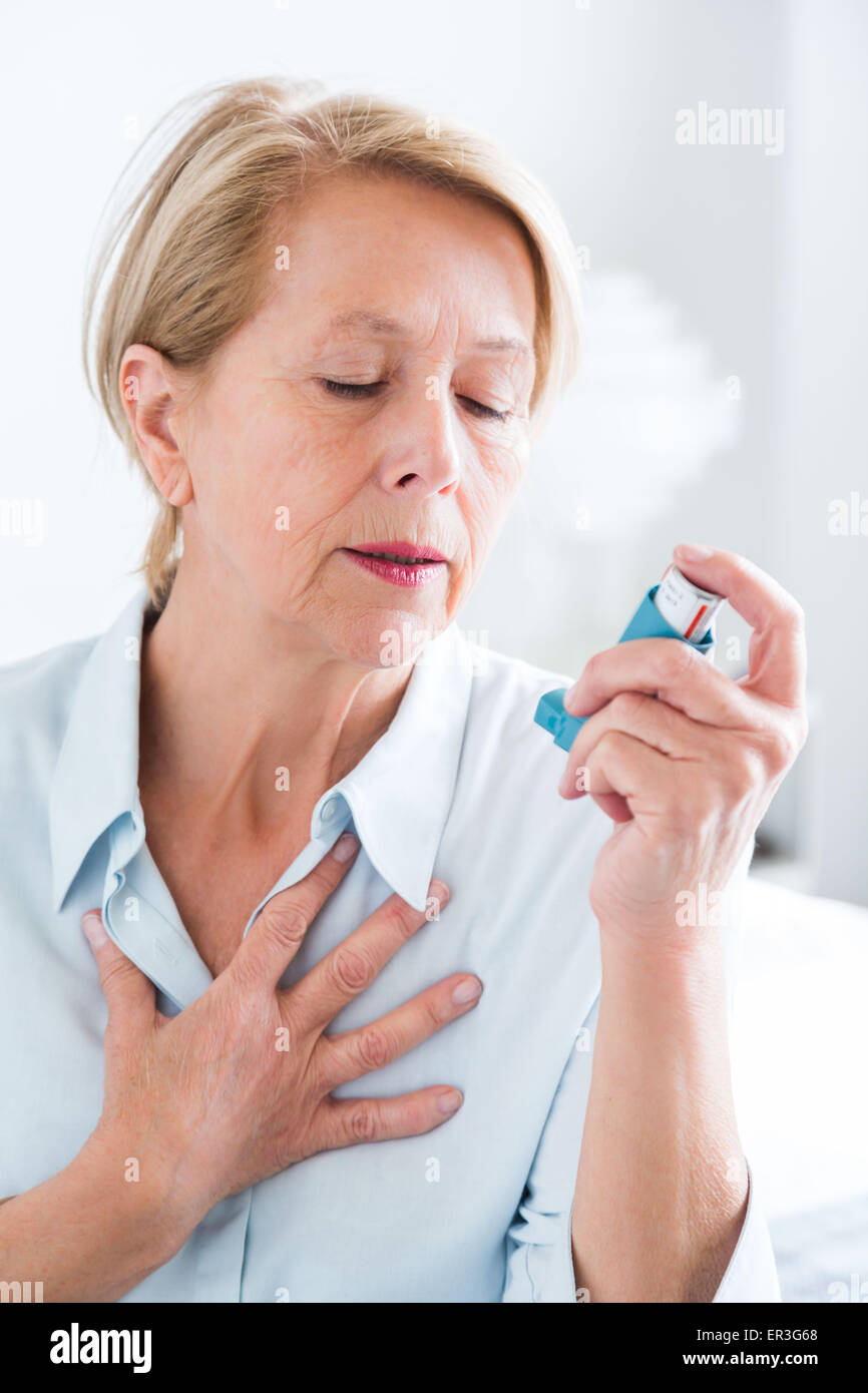 Woman using an aerosol inhaler that contains bronchodilator for the treatment of asthma, The
