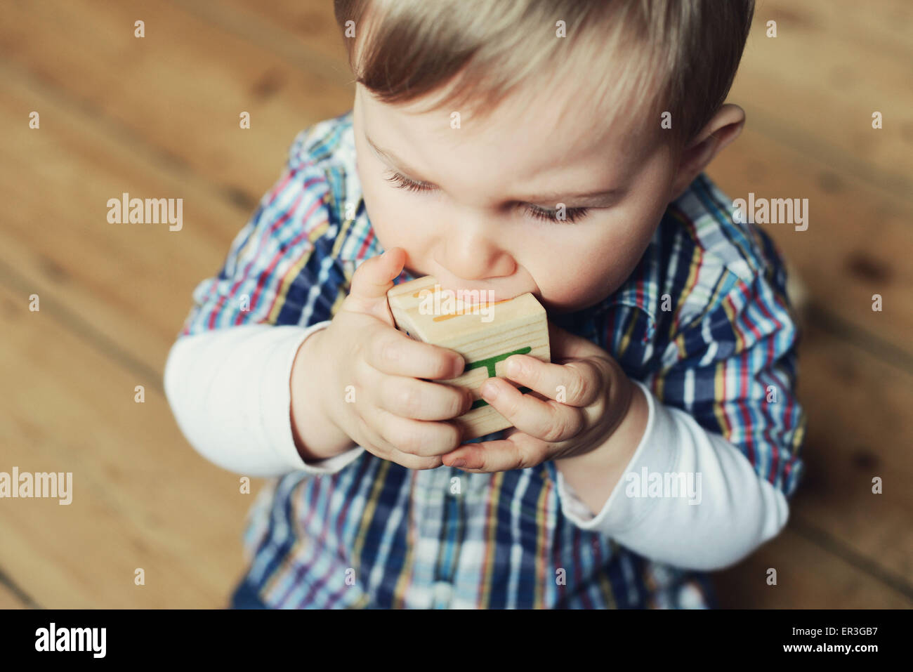 Baby boy chewing on wooden toy block Stock Photo