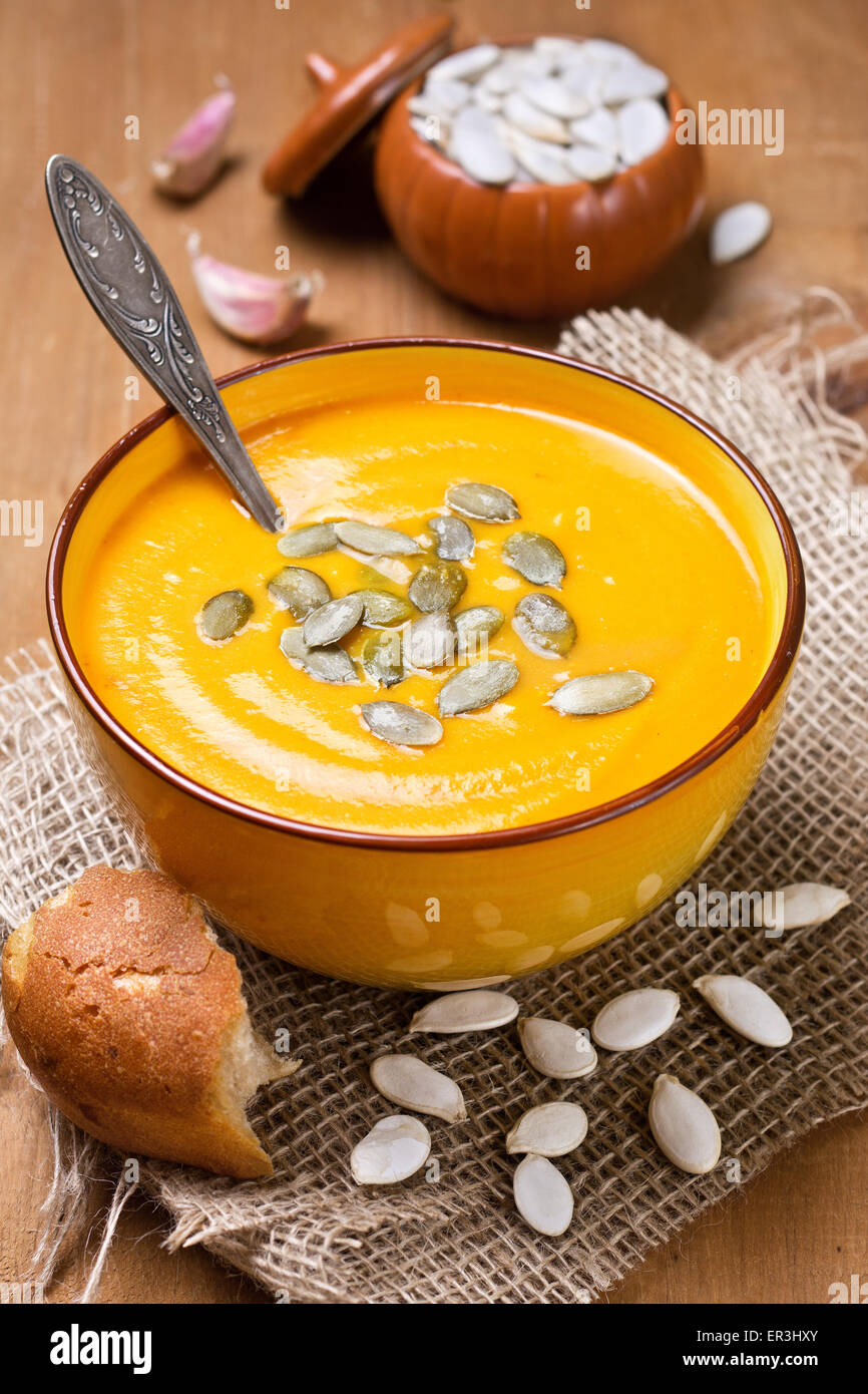 pumpkin soup - puree with pumpkin seeds in a yellow bowl on a wooden background Stock Photo