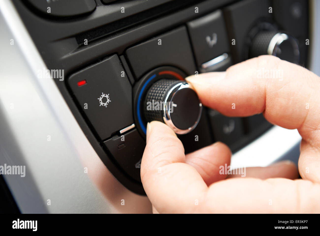Close Up Of Hand Adjusting Car Air Conditioning Control On Dashboard