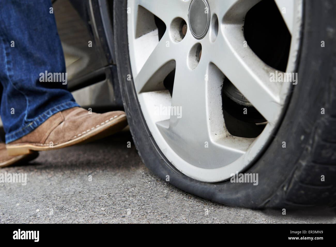Motorist Kicking Flat Tyre On Car Stock Photo