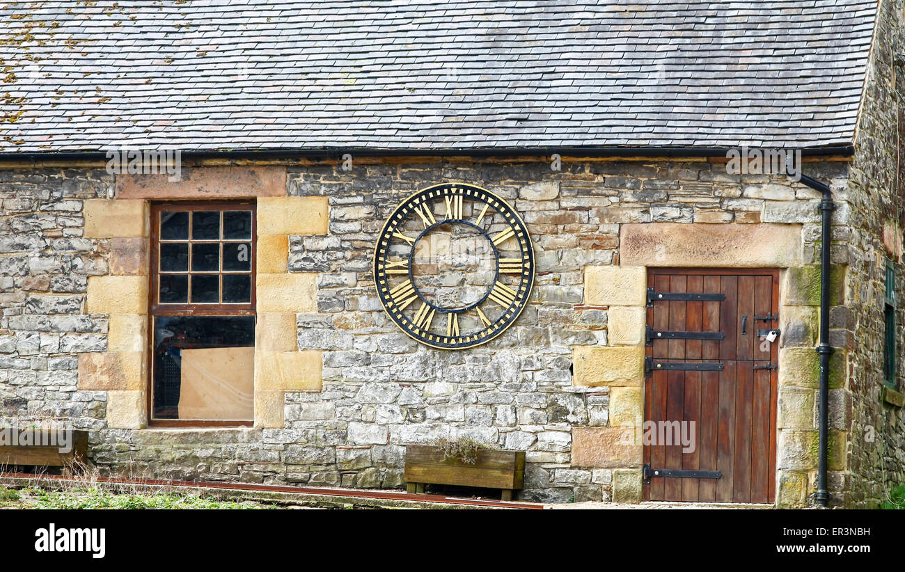 A clock with no fingers or hands on the outside wall of a stone building at Tissington Derbyshire Peak District England UK Stock Photo