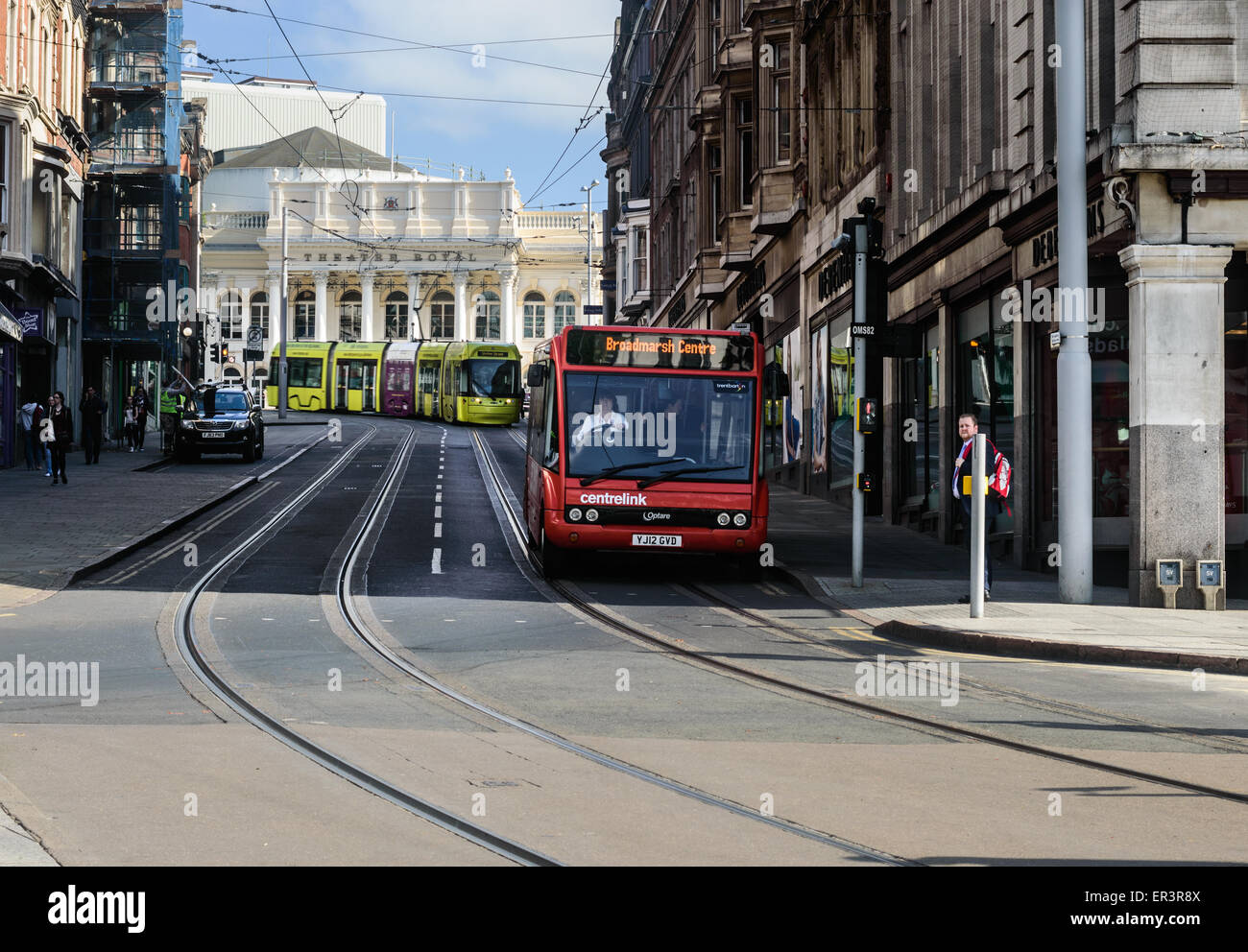A Nottingham NET tram behind a red 'Trent' bus, on Market Street, in Nottingham, England. Stock Photo