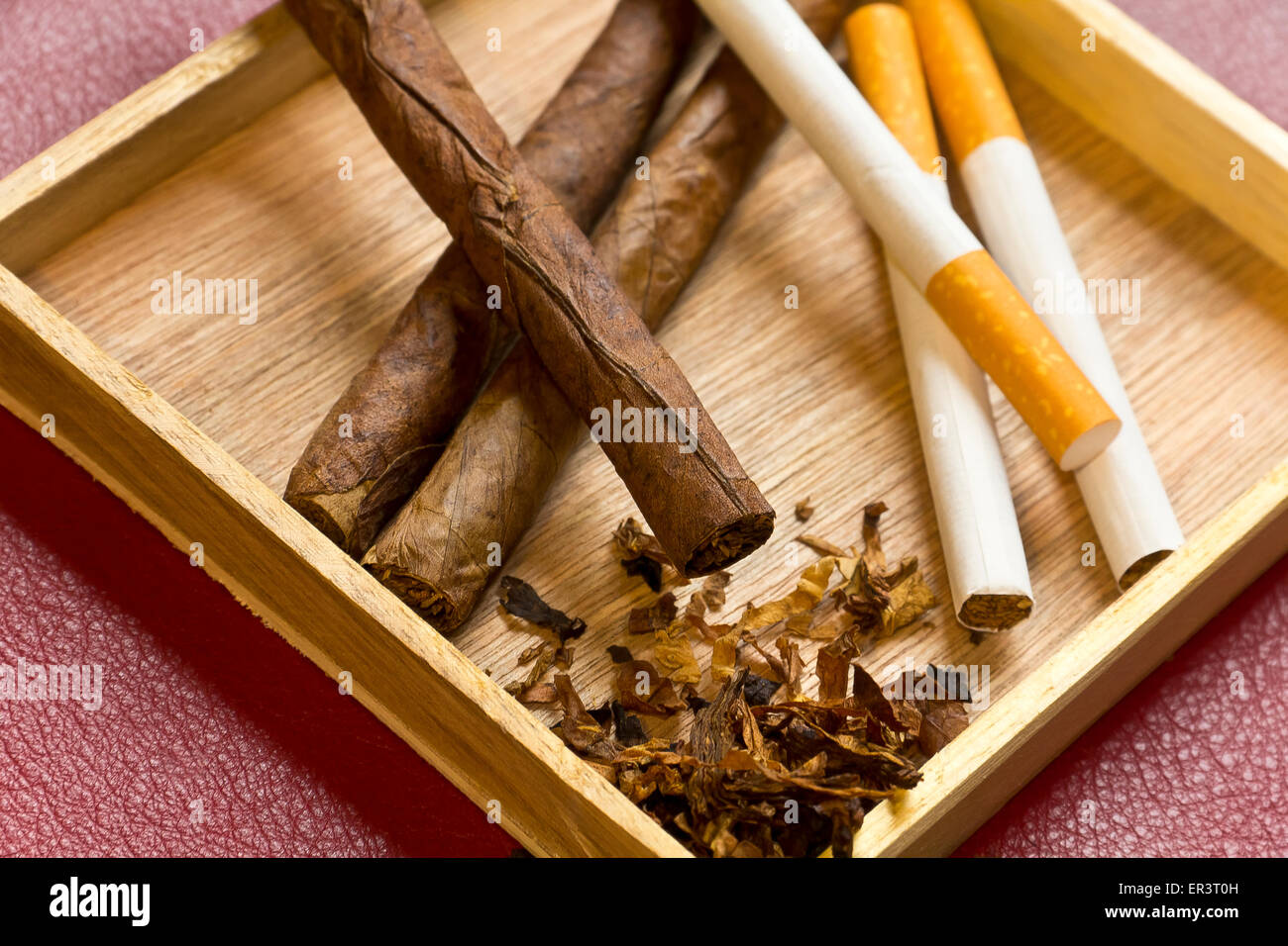 Tobacco, cigarettes, cigars, smoking, etc. on red leather background Stock  Photo