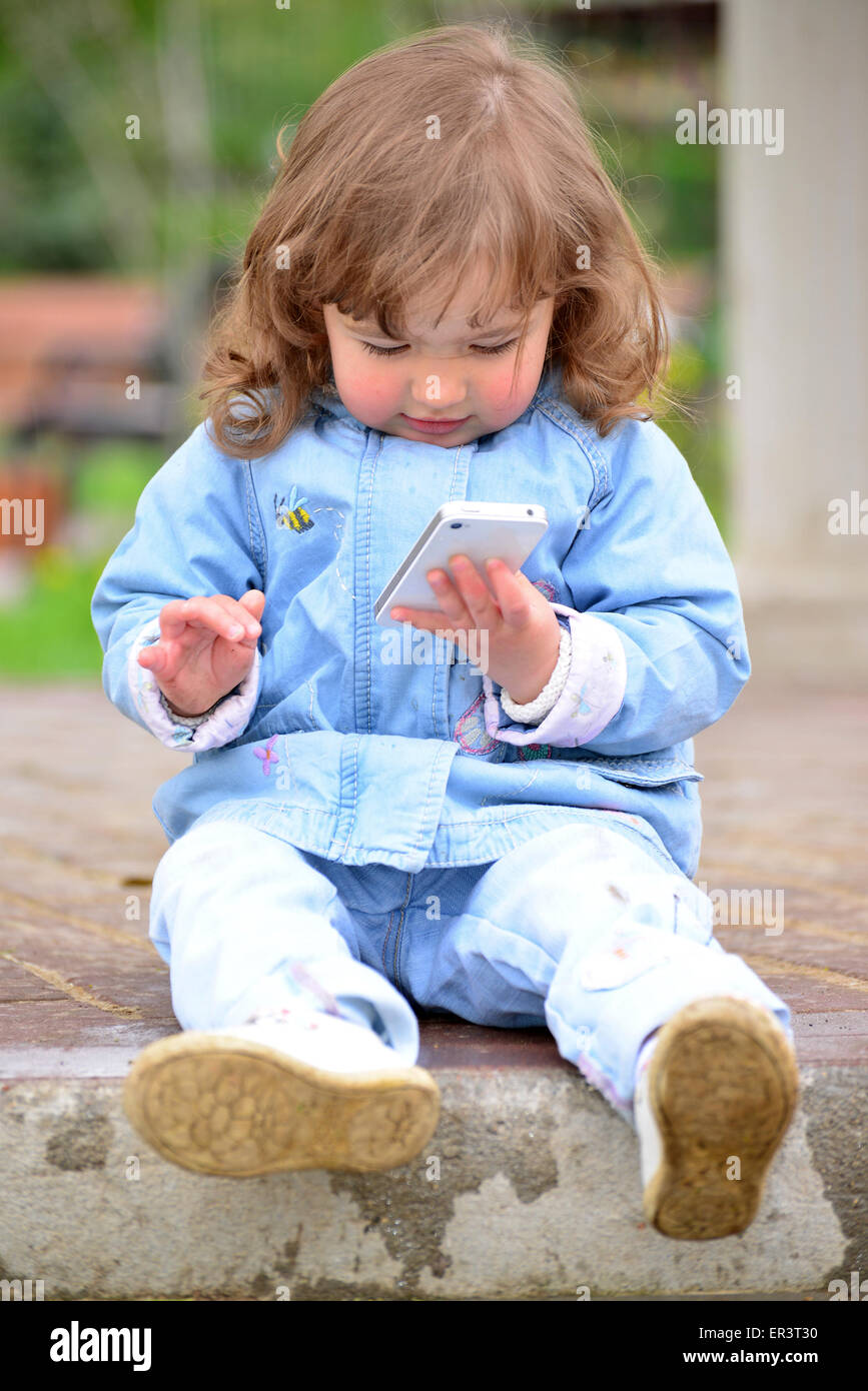 Little girl talking on cell phone against green of Park in summer. Stock Photo