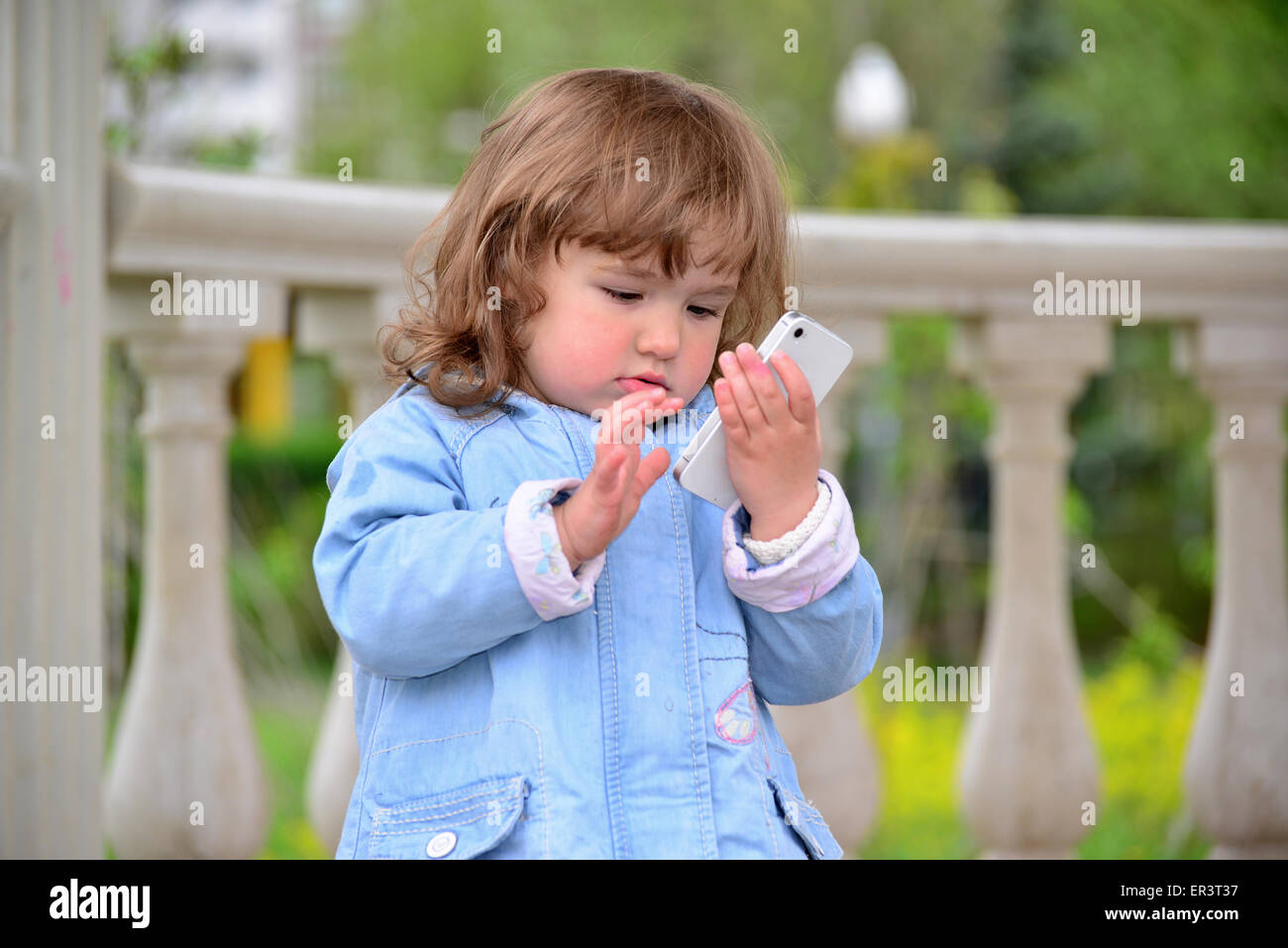 Little girl talking on cell phone against green of Park in summer. Stock Photo