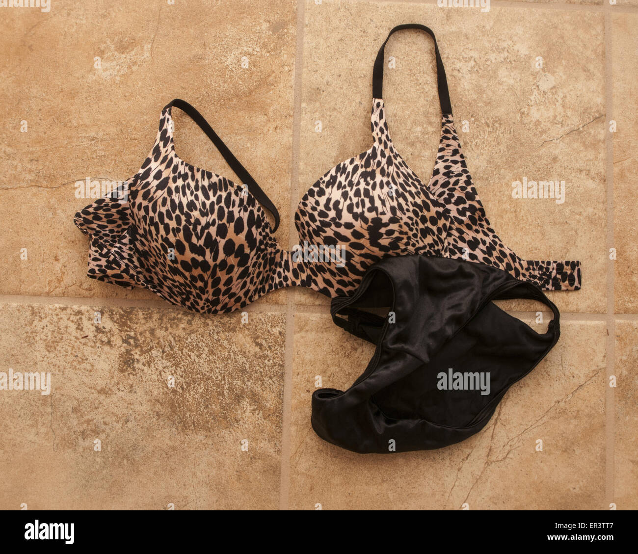 Lingerie, a bra and black panties, lying on a beige tile floor Stock Photo  - Alamy
