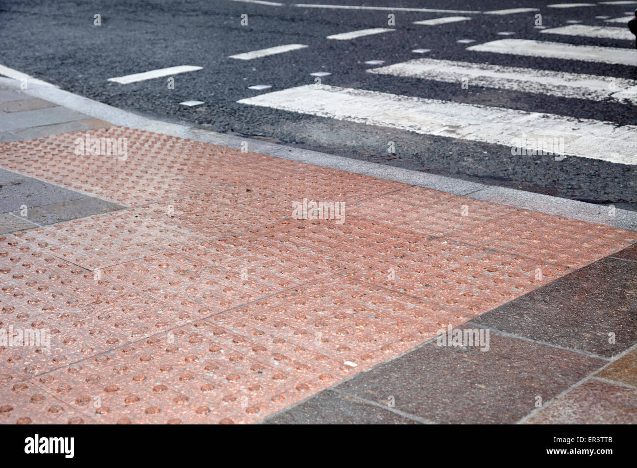 textured pedestrian crossing pavement in the wet in the uk Stock Photo