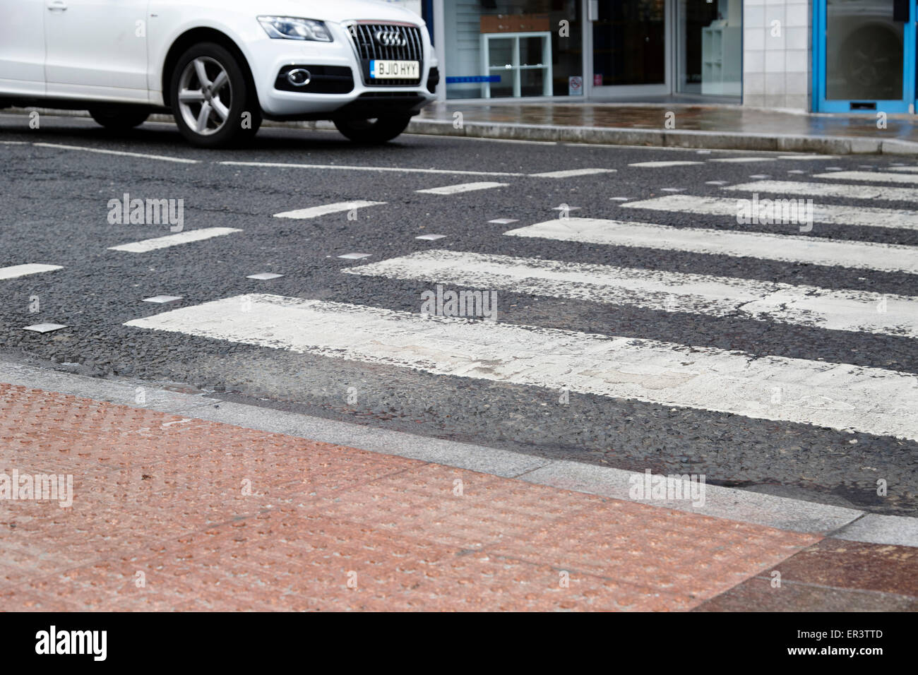 car waiting at textured pedestrian crossing pavement in the wet in the uk Stock Photo