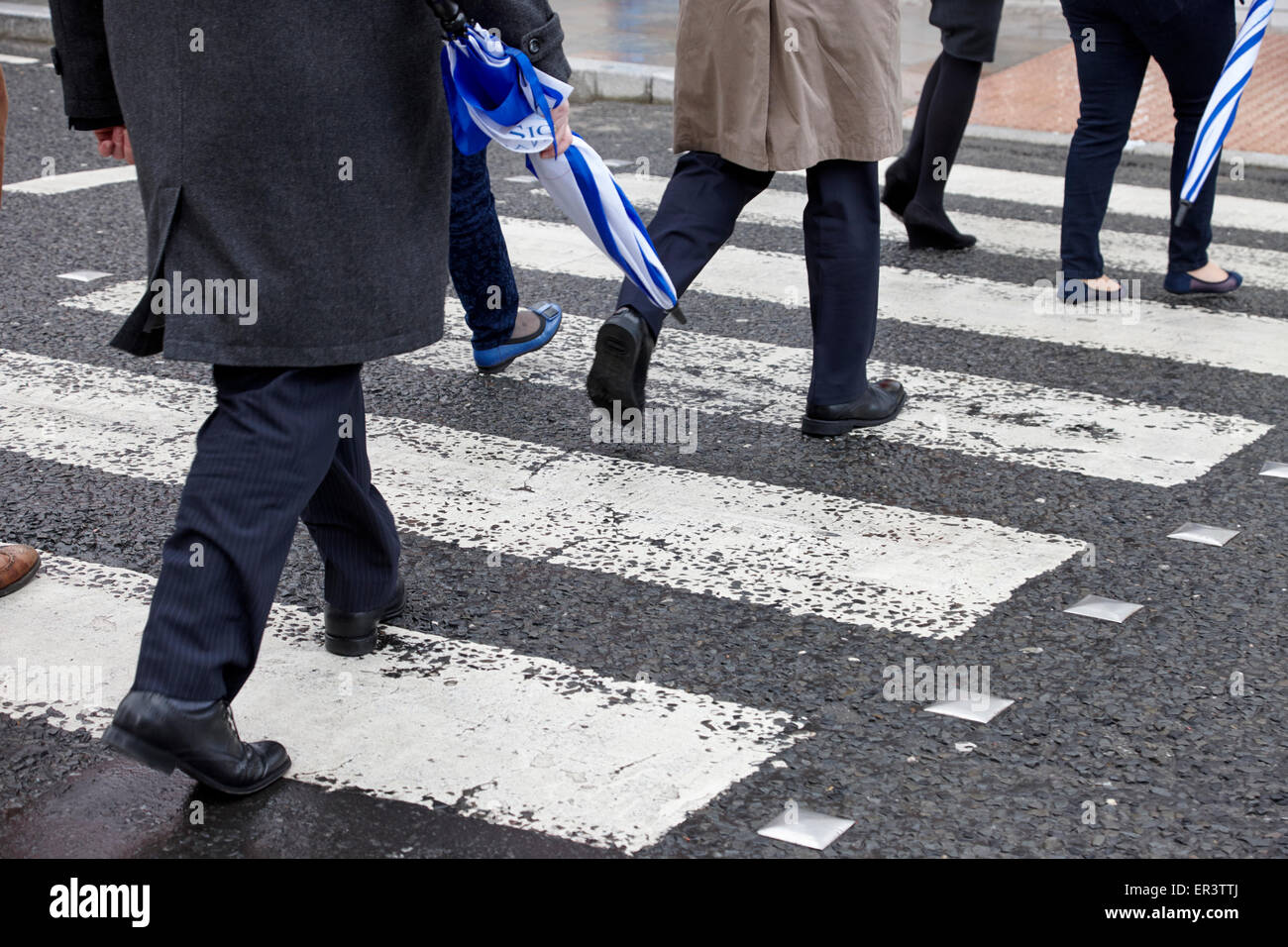 business people crossing wet pedestrian crossing in the uk Stock Photo