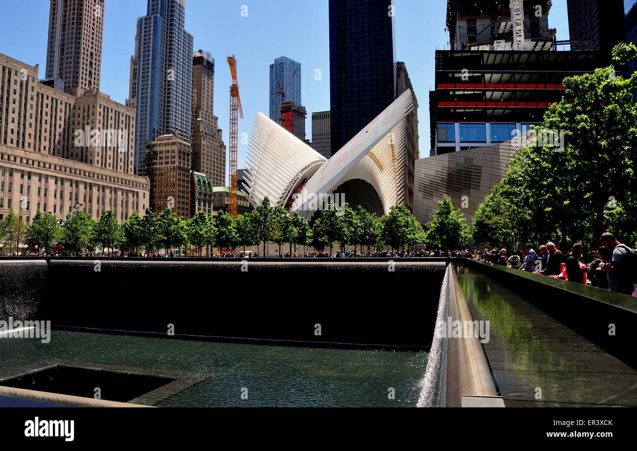 New York City:  North tower waterfalls at 9/11 Memorial with the bird-like wings of architect Santiago Calatrava's PATH hub Stock Photo