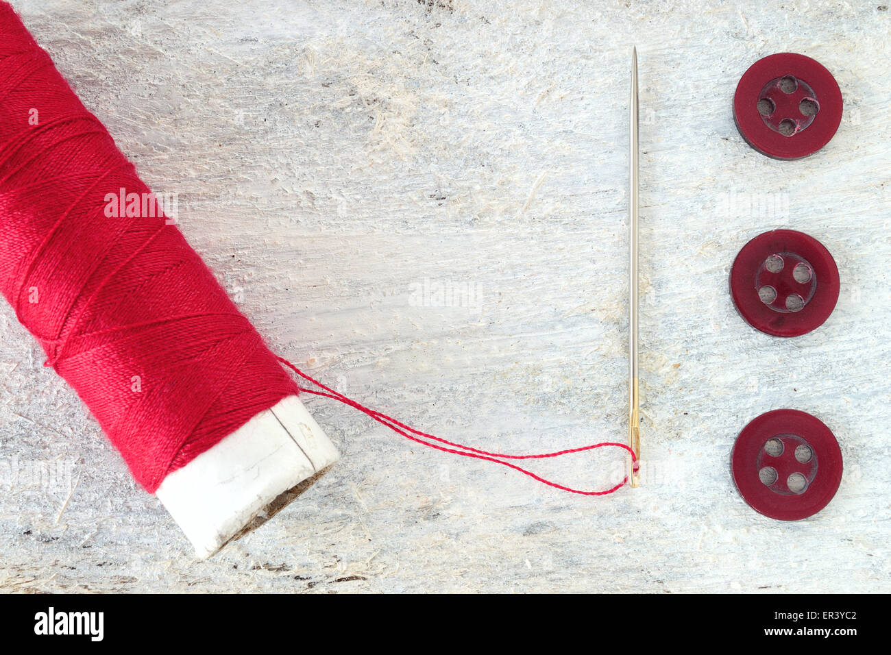 Sewing needle threaded with a red thread ready for sewing. Next , three