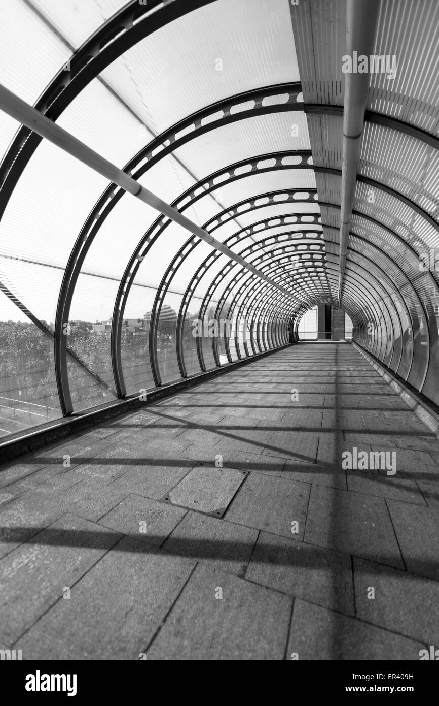 Poplar DLR station high-level walkway, a cable stayed footbridge with curved glass canopy in the London docklands, UK Stock Photo