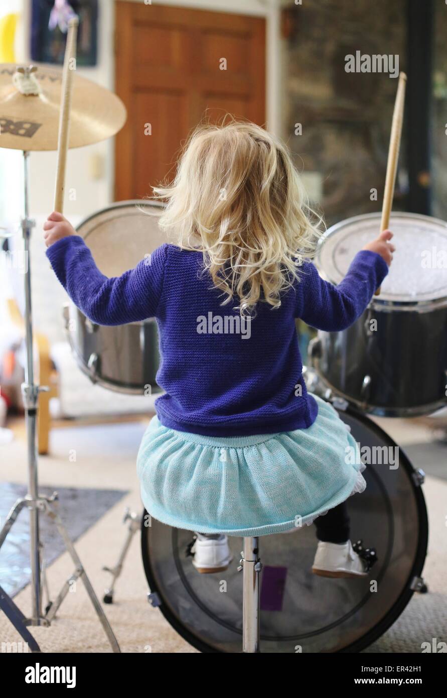 A little girl playing drums as seen from behind. Stock Photo