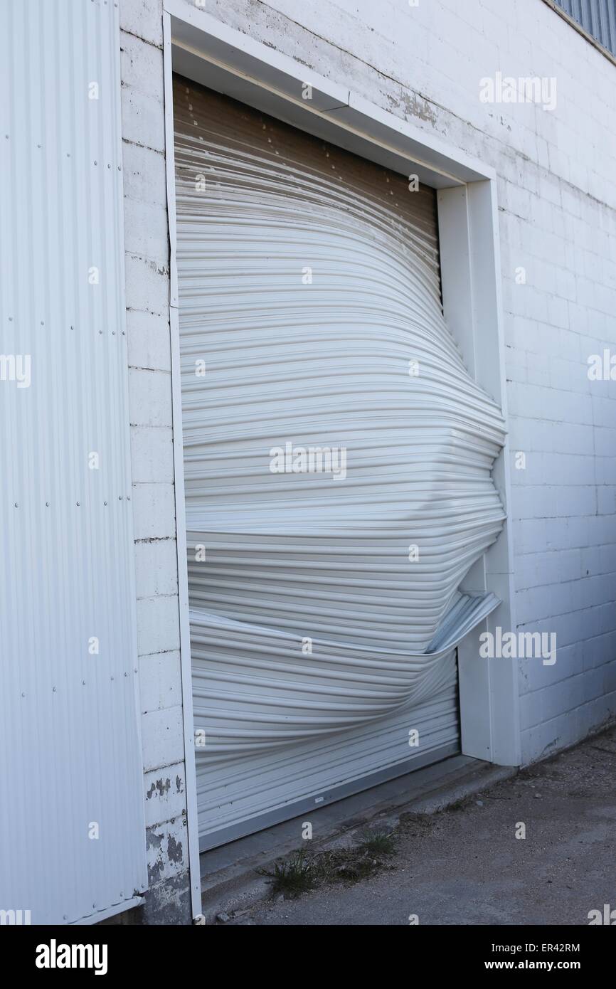 A badly dented and mangled garage door. Stock Photo